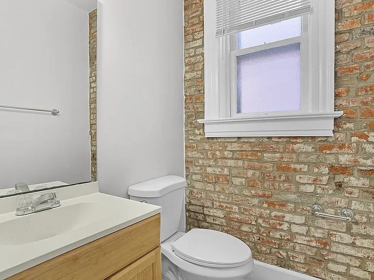 Bathroom with exposed brick detail, classic white trim, vanity, and natural light.