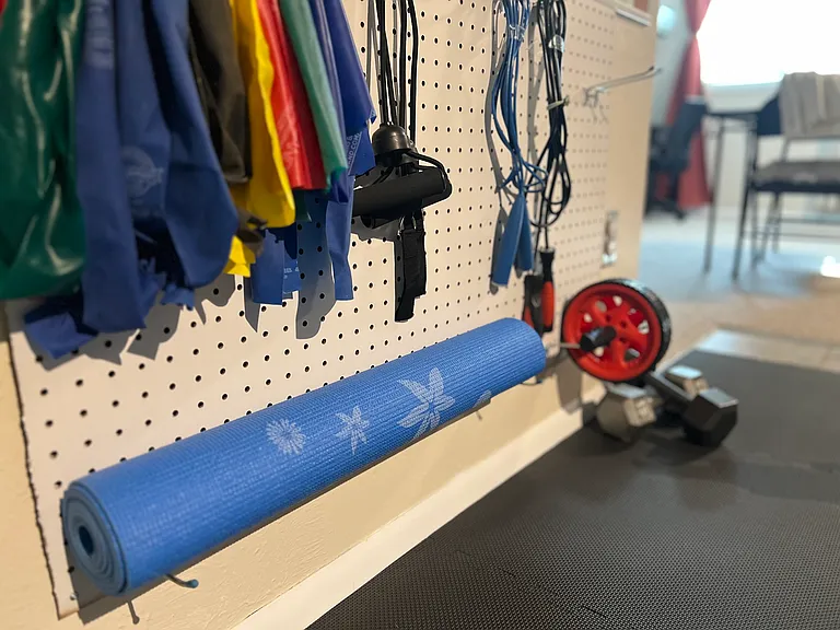 Small exercise nook with resistance bands, yoga mat & dumbbells for light workouts.