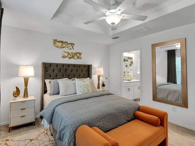Spacious bedroom with a tray ceiling, ceiling fan, bedside lighting, and convenient access to an en-suite bath.