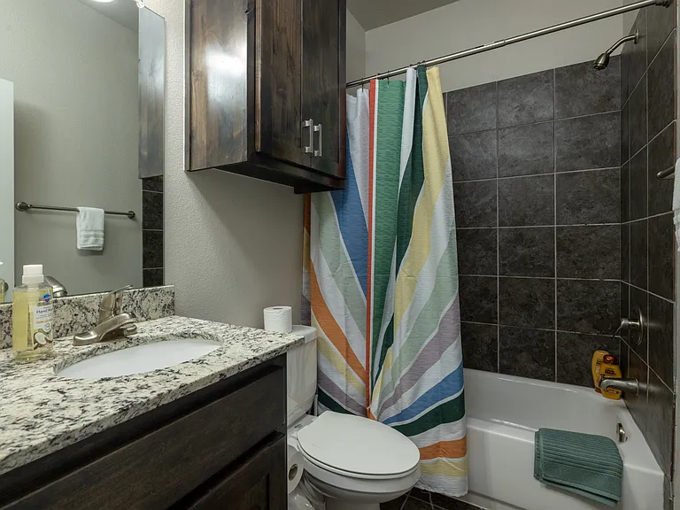 Bathroom 3 has a tub/shower combo and granite cabinet sink with mirror. This bathroom is located upstairs.