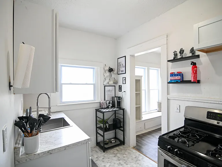 Efficient kitchen with gas range, ample counter space, and a large window for natural light, plus open shelving for storage.