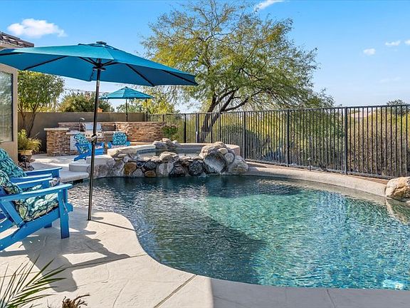 Backyard _ Feel the difference in your skin and swim in the Saltwater pebble-tec pool with two lagoons that allow umbrellas for additional shade. Soak in the 8-person spa with a beautiful waterfall feature. Pool Capable of being heated