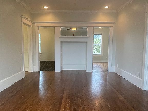 View of living room into secondary bedroom on the left and primary on the right, featuring a faux fireplace and mirrored mantle.