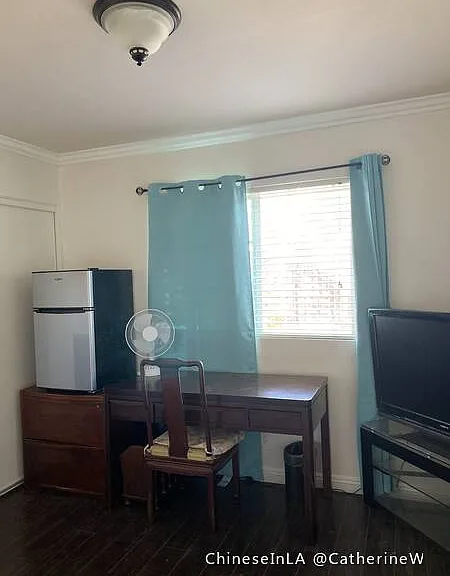 Bedroom 1. Larger room with big closet, fridge, TV and TV stand, desk, chair, twin bed, electric fan, hot water kettle.