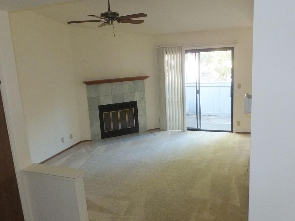 Living room with fireplace and ceiling fan. Slider to balcony.