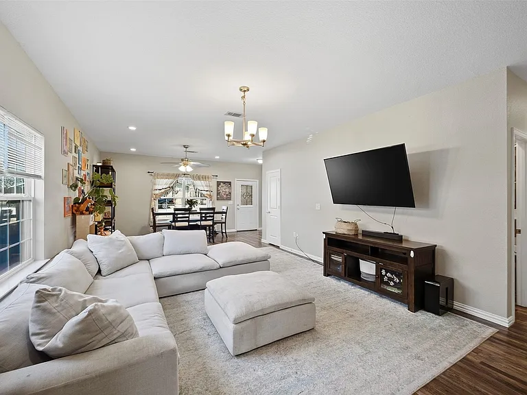 Open-concept living area featuring light-colored walls and wood-finish flooring