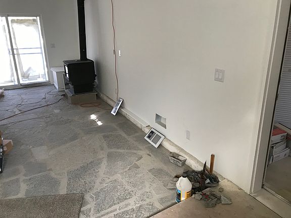 Large entry coming thru front door, stone floor, wood burner stove, deck out the patio door, ramp into entry.