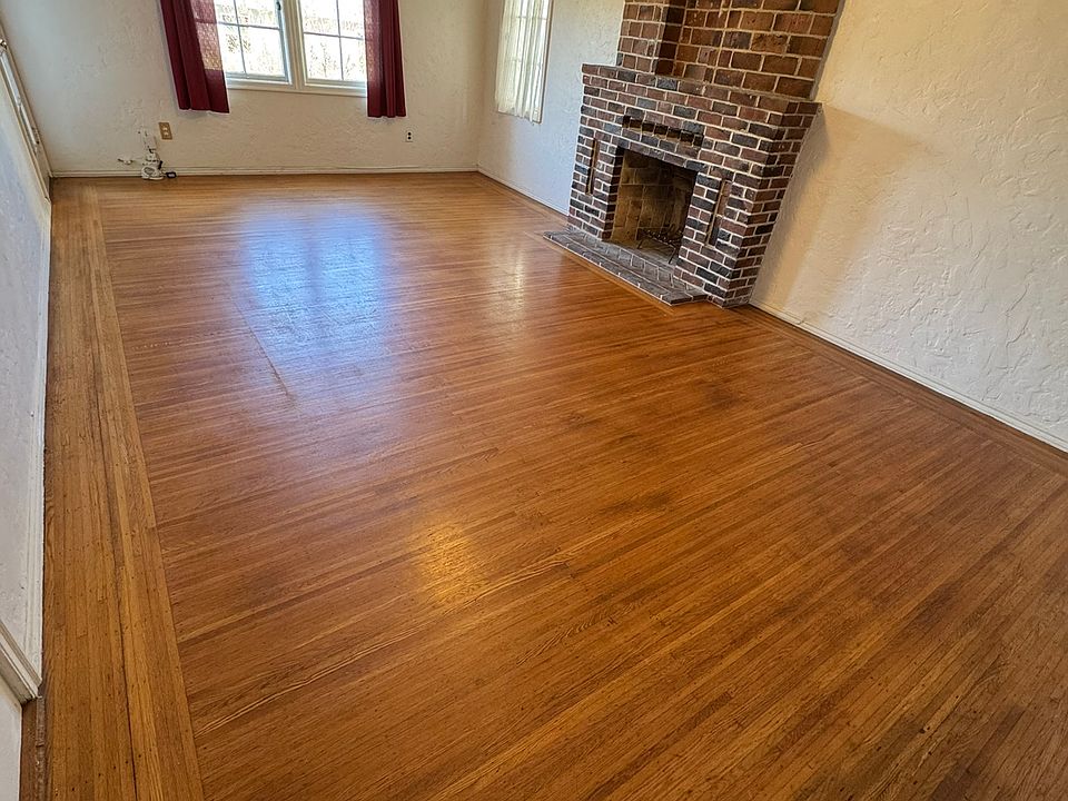 Living room with beautiful hardwood floor, three windows and (non-usable) brick fireplace
