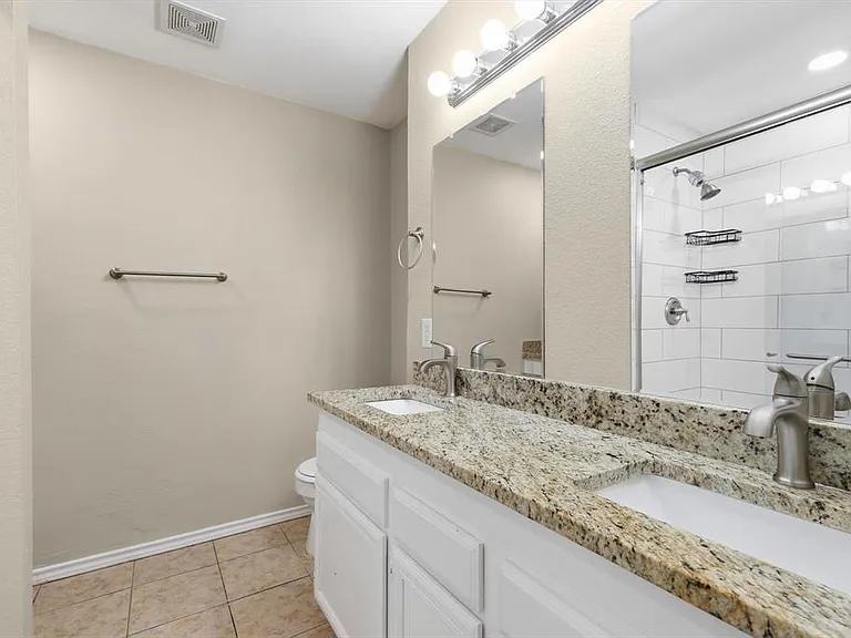 Full bathroom featuring double vanity, a tile shower, and light tile patterned flooring