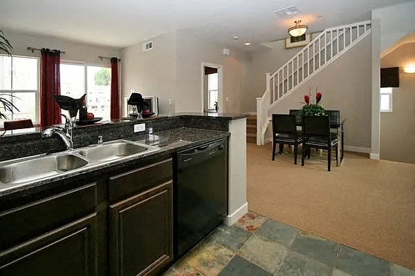 Open kitchen with serving bar and double stainless steel sink at Serenata Townhomes in San Diego, California.