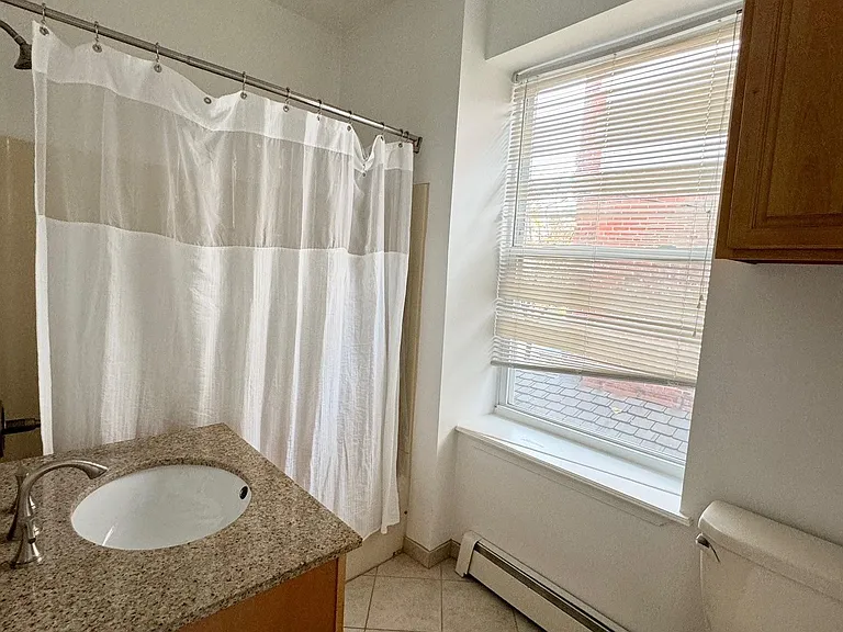 Bathroom w/ maple cabinetry and ceramic tile flooring
