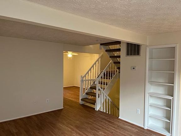 Living room with built in bookshelf floating stairs to upstairs and lower level. Dining area shown in the adjacent room.
