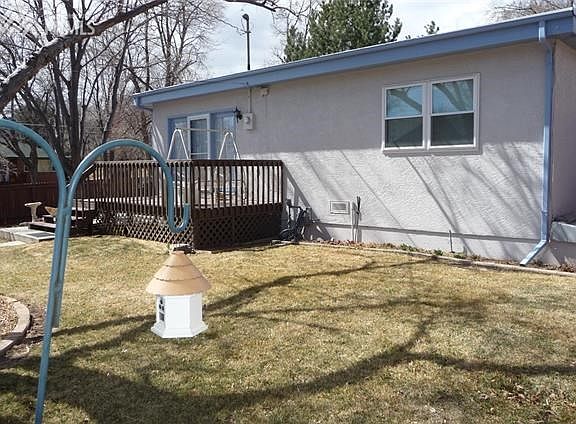 Back side of this well kept stucco home with gorgeous lawn and beautiful perennials.