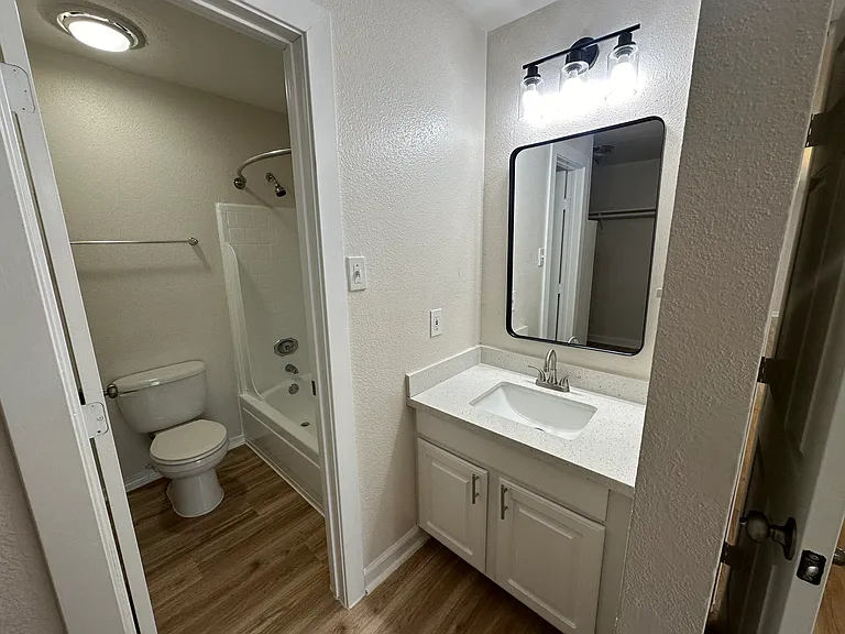 Modern bathroom with sleek vanity, large mirror, and stylish lighting above a bathtub and toilet. Modern bathroom with sleek vanity, large mirror, and stylish lighting above a bathtub and toilet.