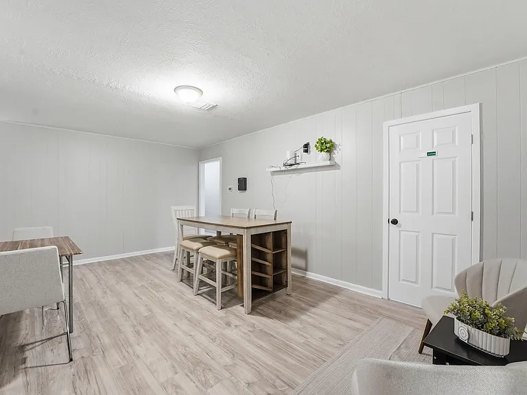 Open dining area with a high-top table, additional seating, and durable wood-look flooring for easy shared meals.