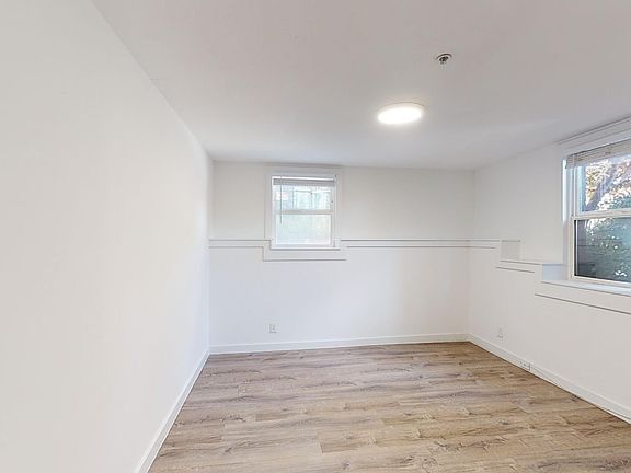 Spacious room with wood-like flooring and a large window offering natural light