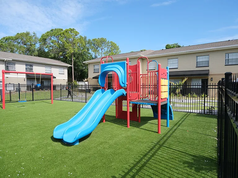 Inviting playground with vibrant slides and swings set against lush greenery, ideal for family-friendly living.