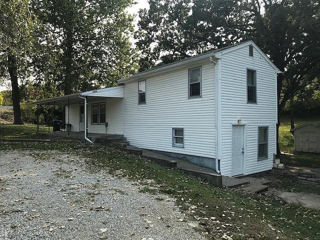 covered front porch, gravel driveway, storage shed in the back