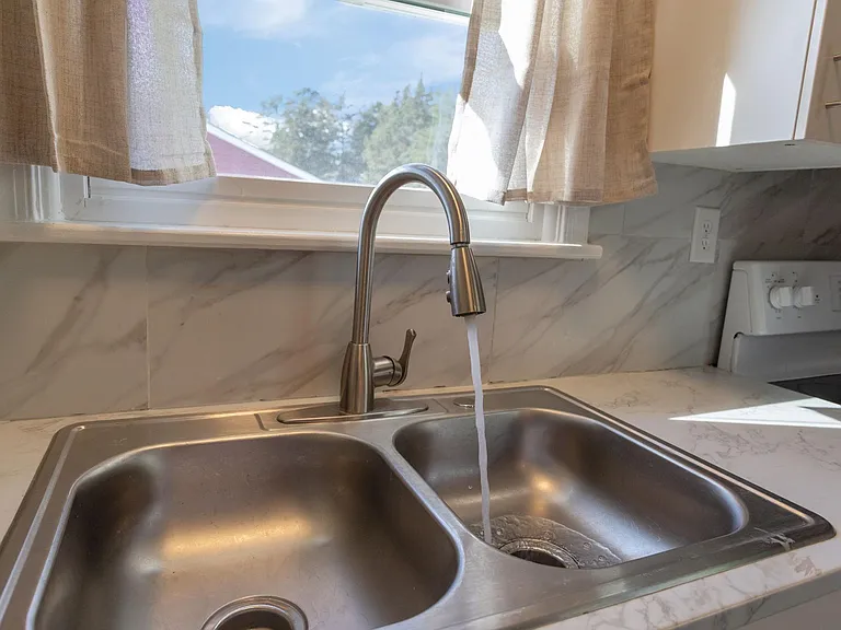 Kitchen sink area with a double-basin stainless sink, high-arc faucet, and window over the counter for natural light.
