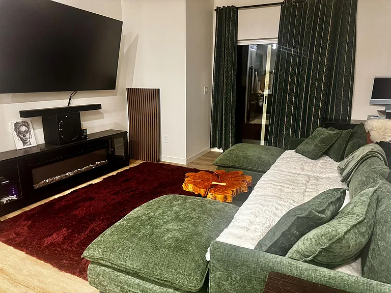 Comfortable living room with sectional seating, wall-mounted TV and media console, plus sliding-door access to the patio.