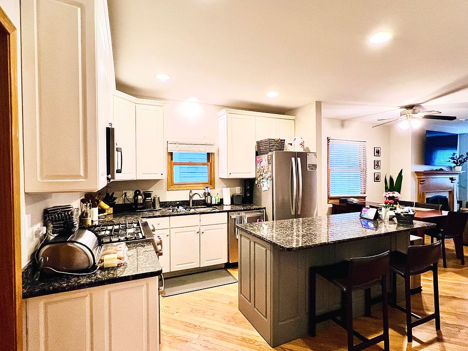 Spacious open concept kitchen with white cabinets, extra large island with electrical outlets, and up to 4 counter stools. Faces dining area and main living room.