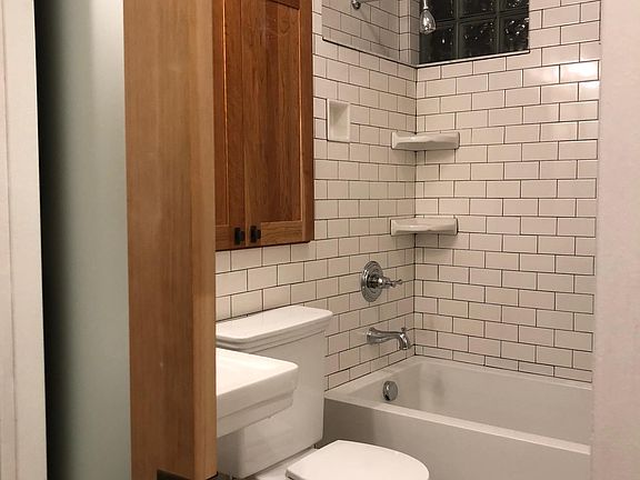 Bathroom with pocket door, custom cabinets and lots of tile.