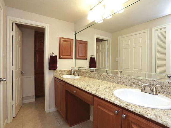 The bathroom features stunning granite countertops, dual sinks with polished nickel faucets, polished nickel wall lights, stained maple cabinetry, and more.