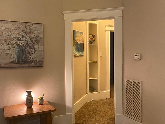 Living room leading to bedrooms and full bath with original built in shelves for you treasures or books.
