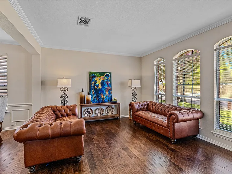 Spacious living area featuring rich wood-finish flooring, elegant crown molding, and wainscoting details