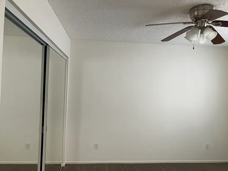 Between 1 has closet glass doors and fan.