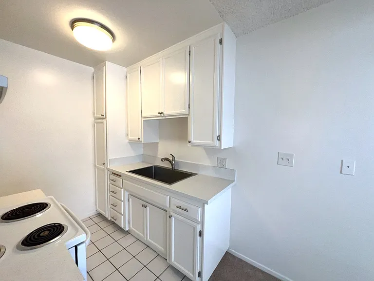 Kitchen area with wood cabinets, new quartz counters & single bowl sink