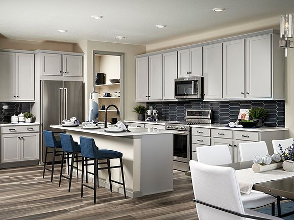 A modern, open-concept kitchen with white cabinets, a gray tile backsplash, and a central island wit
