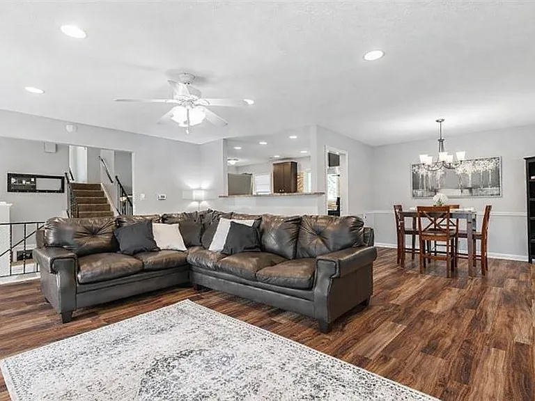 Open-concept living area with sectional seating, durable wood-look floors, and a defined dining space near the kitchen pass-t