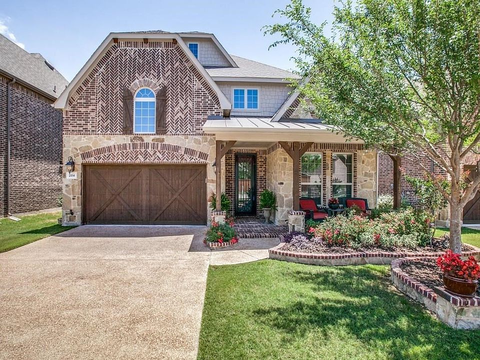 Lovely brick and stone facade with cedar garage door and custom stone work.