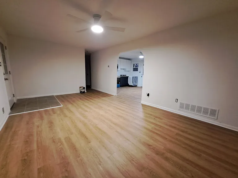 Large living room with new floors looking toward kitchen.