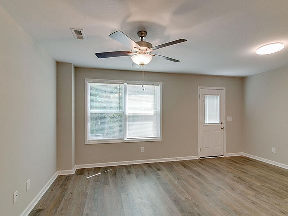 Great Room with Ceiling Fan and Nice Natural Light. Back Door to Patio - Trees behind
