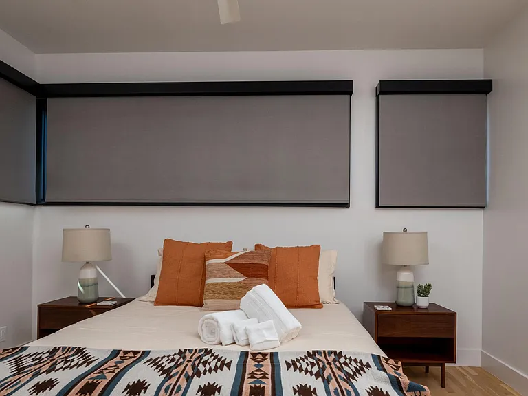 Bedroom 2 features a queen bed and windows on two sides, with room-darkening shades for restful sleep and added privacy.