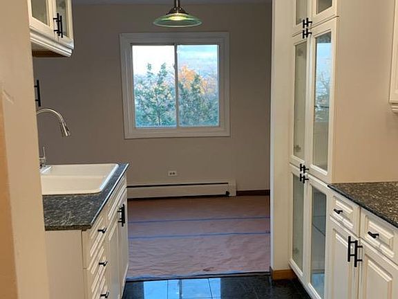 kitchen with white glass open cabinets, black granite counter tops and granite floors.