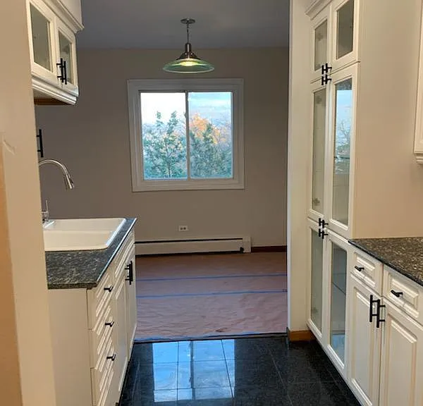 kitchen with white glass open cabinets, black granite counter tops and granite floors.