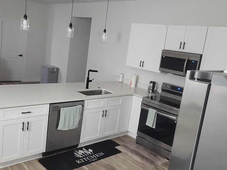 Open kitchen with a large island, ample white cabinetry, and stainless-steel appliances including microwave and dishwasher.