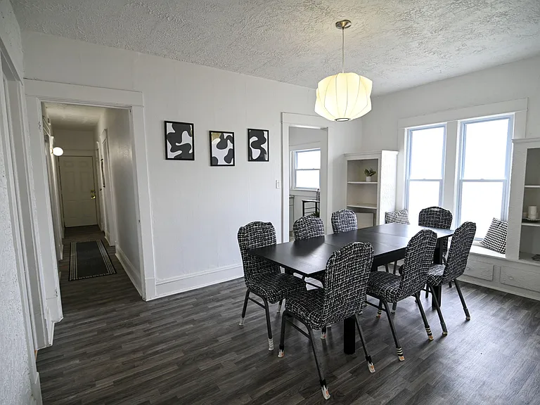Dining area with a large table for group meals, overhead pendant lighting, and nearby built-in shelving by the windows.