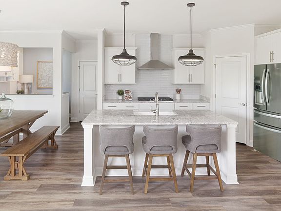A bright, gourmet kitchen equipped with pendant lighting fixtures and beautiful hardwood flooring.