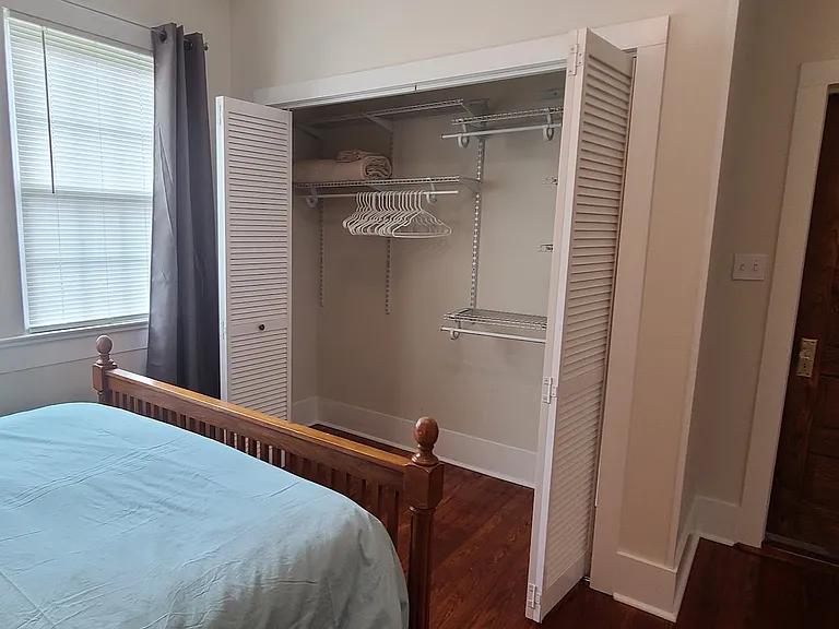 Large closet with adjustable shelving in queen bedroom.