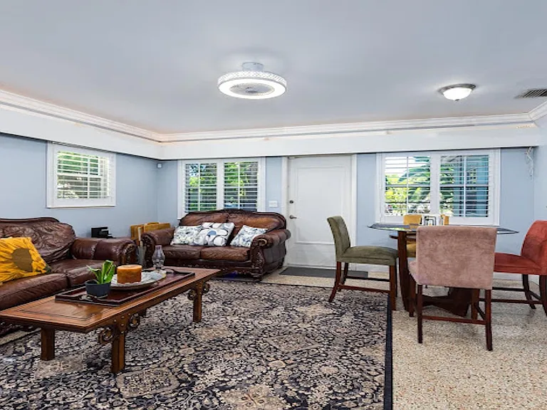 Open-concept living area with comfortable seating, large windows with shutters, and adjacent dining nook for everyday meals.