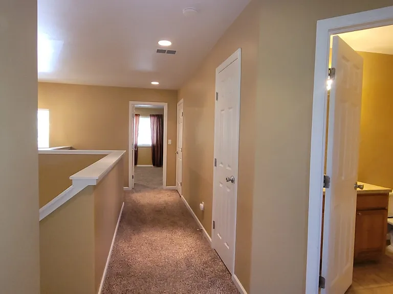 Looking down the hall from the first bedroom's door to master and guest bathroom to the right. First door after bathroom is the linen closet. Second door is the laundry with an alcove across the hall.