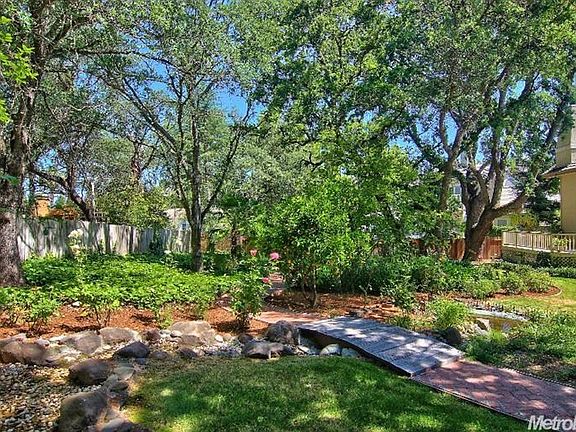 Meandering water feature with fountain and pond, walking paths and lush greenery.
