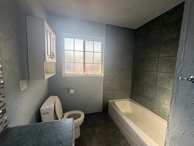 The guest bathroom has been partially renovated and features a new backsplash, updated lighting, and modern finishes that add style and functionality.