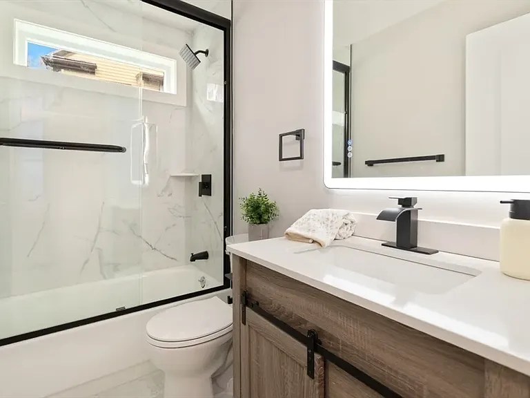 Modern full bath featuring a deep soaking tub and sleek glass doors_pristine and move-in ready.