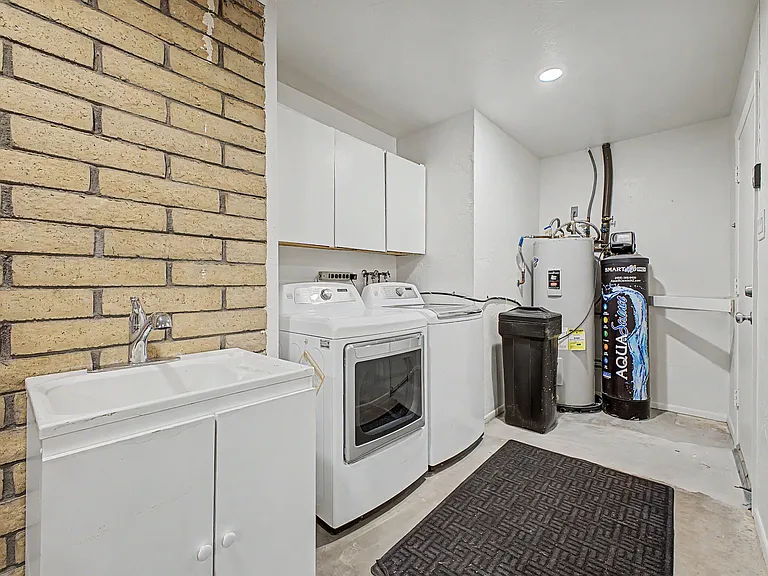Dedicated laundry area with washer/dryer, utility sink, and overhead cabinets for supplies and extra storage.