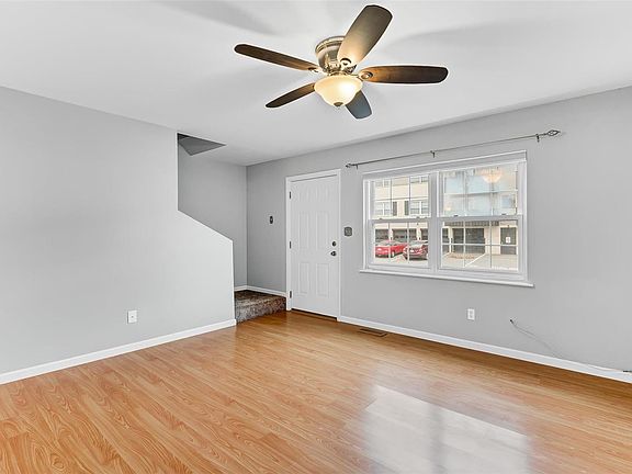 Living room with ceiling fan and light.  Windows provide natural light throughout the living room.